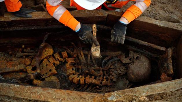 A field archaelogist uses a brush on a skeleton in an open coffin during the excavation of a late 18th to mid 19th century cemetery under St James Gardens near Euston train station.(AFP)