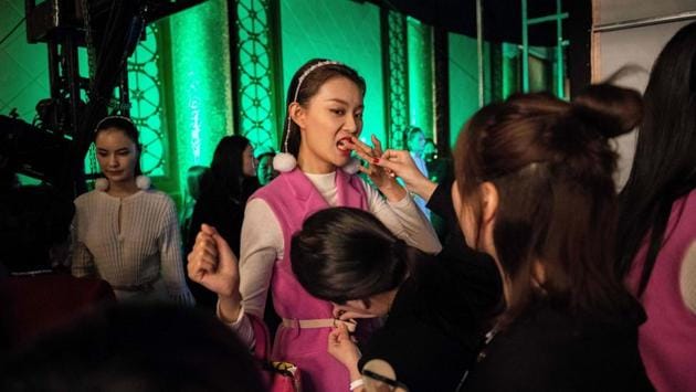 A model (C) tries to remove lipstick from her teeth backstage before the presentation of the Rabbit-Warm collection by Zhuang Ganran during China Fashion Week in Beijing, China. (Nicolas Asfouri / AFP)