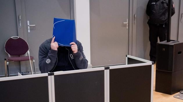 Former nurse Niels Hoegel, accused of killing more than 100 patients in his care, hides behind a folder as he arrives in the courtroom, in Oldenburg, northern Germany, for the start of his trial. (Julian Stratenschulte / Pool / AFP)