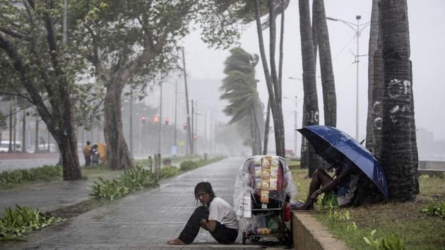 A streetside vendor shivers in the rain as weather patterns from Typhoon Yutu affect Manila Bay, in the Philippines. (Noel Celis / AFP)