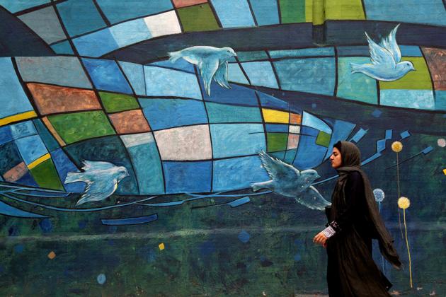 An Iranian woman walks past colourful walls in the capital Tehran. Iran's President Hassan Rouhani said the Islamic republic ‘will proudly bypass sanctions’ by the United States that took effect on Monday targeting the country's oil and financial sectors.(AFP)