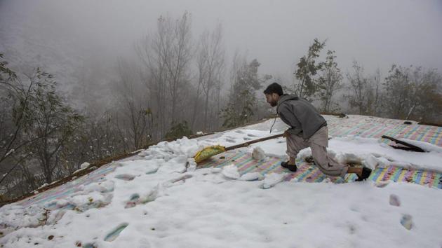 A man clears snow from the roof top of his mud-house on the out skirts of Srinagar on Sunday.(PTI Photo) A man clears snow from the roof top of his mud-house on the out skirts of Srinagar on Sunday.(PTI Photo)