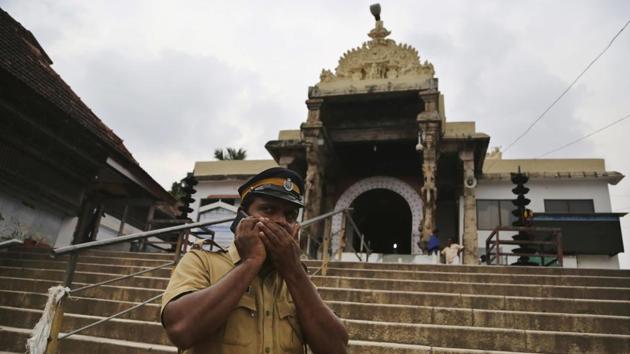An Indian police officer talks on a phone while standing guard outside the 16th-century Sree Padmanabhaswamy temple in Thiruvananthapuram, Kerala. Synagogues, mosques, churches and other houses of worship are routinely at risk of attack in many parts of the world. And so worshippers themselves often feel the need for visible, tangible protection even as they seek the divine. (Aijaz Rahi / AP)