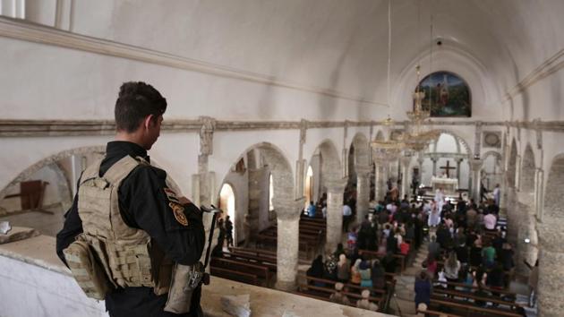 A Christian militiaman stands guard during Easter mass in Qaraqosh, Iraq. In Iraq, houses of worship have been favourite targets for the warring parties since the 2003 US-led invasion that toppled Saddam Hussein, unleashing a widespread violence and a sectarian war. Since then, Iraqis have welcomed the security blanketing mosques, churches and temples. (Maya Alleruzzo / AP)