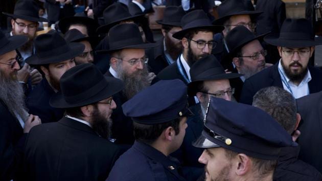 New York City police officers watch as rabbis gather for a group photo at the Chabad-Lubavitch World Headquarters in New York. The NYPD has increased patrols at houses of worship in light of the recent fatal shooting at a synagogue in Pittsburgh. At risk of attack in many parts of the world, even worshippers in America are not immune after the recent Pittsburg shooting. (Mark Lennihan / AP)