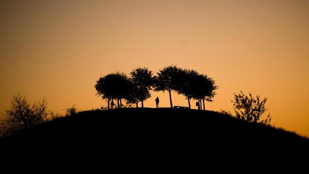 A man takes a stroll as the sun rises behind the Kronsberg hill in Hanover, northern Germany. (Julian Stratenschulte / dpa / AFP) A man takes a stroll as the sun rises behind the Kronsberg hill in Hanover, northern Germany. (Julian Stratenschulte / dpa / AFP)