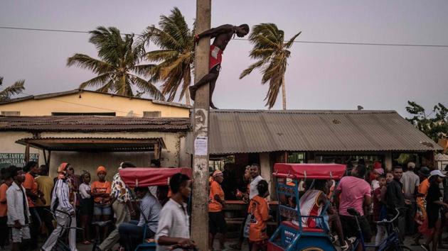 A man dangles from an electricity pole as he watches supporters of Madagascar presidential candidate Andry Rajoelina, streaming towards a rally in Tulear, Madagascar. (Marco Longari / AFP) A man dangles from an electricity pole as he watches supporters of Madagascar presidential candidate Andry Rajoelina, streaming towards a rally in Tulear, Madagascar. (Marco Longari / AFP)