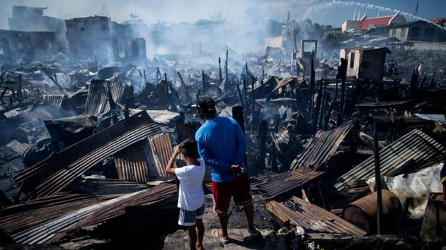 Residents look at destroyed houses after a fire engulfed a slum area in Navotas along Manila Bay, Philippines. (Noel Celis / AFP) Residents look at destroyed houses after a fire engulfed a slum area in Navotas along Manila Bay, Philippines. (Noel Celis / AFP)