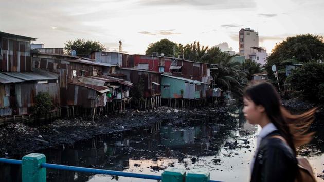 A girl walking past houses on the bank of Xuyen Tam canal in Ho Chi Minh City. Thousands of these makeshift homes are set to be demolished under long-promised government plans to redevelop the city’s “black canals” -- nicknamed for the darkened hue of their waste-strewn waters -- where thousands live with no legal title to the land. (Kao Nguyen / AFP)