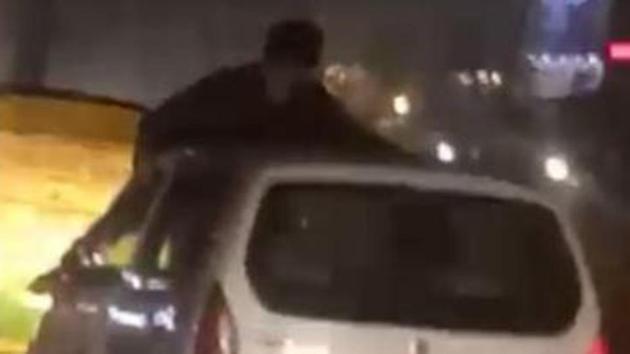 A video grab showing the man hanging on the roof of the car clinging on to the windowpanes. (HT Photo) A video grab showing the man hanging on the roof of the car clinging on to the windowpanes. (HT Photo)