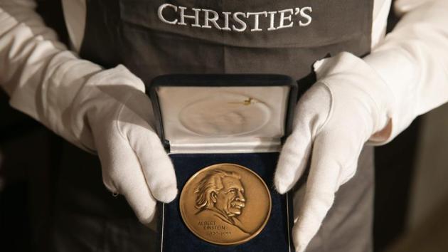 A gallery employee holds an Albert Einstein Medal awarded to Stephen Hawking. The items are only a small selection from Hawking’s archive, which his family is donating to the nation in lieu of paying inheritance tax. The auction funds will go to the family although the money raised from selling the wheelchair will be donated to the Motor Neurone Disease Association and the Stephen Hawking Foundation. (Daniel Leal-Olivas / AFP File)