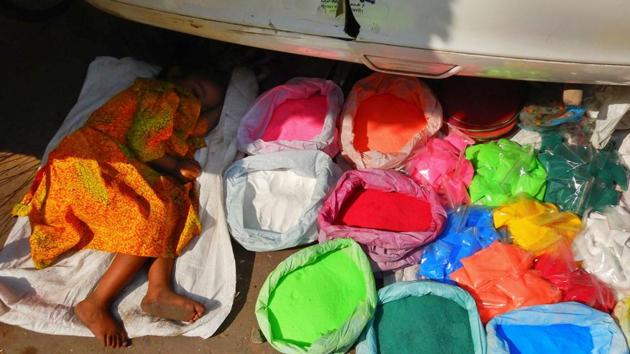 A young girl sleeps next to bags of coloured powder under a car at a market in New Delhi. (Dominique Faget / AFP) A young girl sleeps next to bags of coloured powder under a car at a market in New Delhi. (Dominique Faget / AFP)