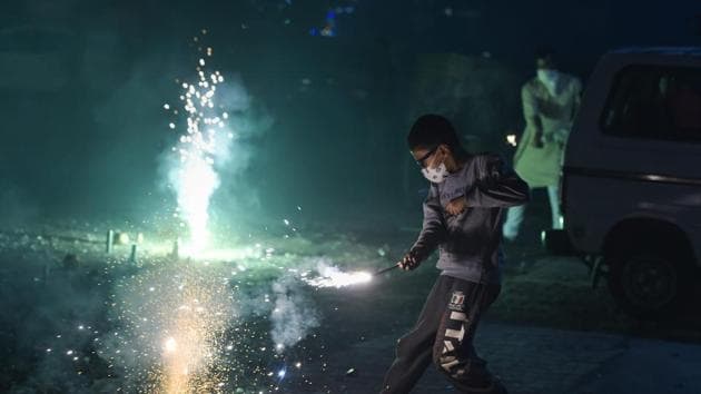 A boy wearing pollution mask burns crackers during Diwali celebrations, in New Delhi, Wednesday, Nov. 7, 2018.(PTI)