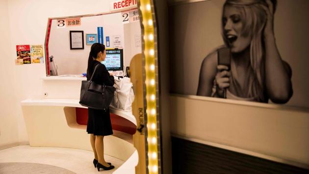 A woman pays for a solo booth at the reception of a karaoke parlour. Six years ago, the Koshidaka karaoke chain realised that some 30% of its customers in certain locations came on their own, so it set up “1Kara”, tiny booths for solo singers. Now the firm runs a network of eight speciality karaoke parlours that each sees “tens of thousands” of crooners flock to its solo booths, said Daiki Yamatani, a spokesman for the chain. (Behrouz Mehri / AFP) A woman pays for a solo booth at the reception of a karaoke parlour. Six years ago, the Koshidaka karaoke chain realised that some 30% of its customers in certain locations came on their own, so it set up “1Kara”, tiny booths for solo singers. Now the firm runs a network of eight speciality karaoke parlours that each sees “tens of thousands” of crooners flock to its solo booths, said Daiki Yamatani, a spokesman for the chain. (Behrouz Mehri / AFP)