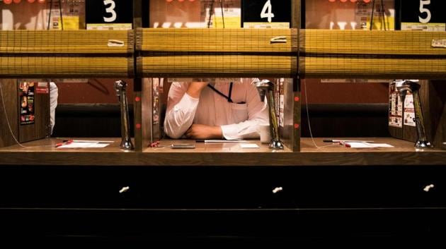 A customer waits in a partitioned booth after ordering ramen noodles. “We were doing this even before the solo activities trend started. This ‘personal space’ concept has been well received in foreign markets too” said Satomi Nozaki, spokeswoman at the popular chain, which also has outlets overseas. (Behrouz Mehri / AFP) A customer waits in a partitioned booth after ordering ramen noodles. “We were doing this even before the solo activities trend started. This ‘personal space’ concept has been well received in foreign markets too” said Satomi Nozaki, spokeswoman at the popular chain, which also has outlets overseas. (Behrouz Mehri / AFP)