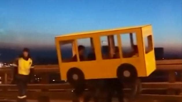 The video shows the men walking across the bridge carrying the pretend-bus over their heads. (Screengrab from video) The video shows the men walking across the bridge carrying the pretend-bus over their heads. (Screengrab from video)