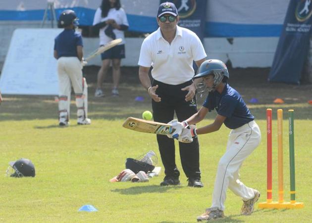 Tendulkar trains a child in the batting skill (the act of hitting the cricket ball with a cricket bat to score runs or prevent the loss of one’s wicket) at Tendulkar Middlesex global academy at the Bishop’s school in Camp on Thursday. (SHANAKAR NARAYAN/HT PHOTO)