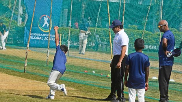 Tendulkar trains a child in the bowling skill (the action of propelling the ball toward the wicket defended by a batsman) at Tendulkar Middlesex global academy at the Bishop’s school in Camp on Thursday. Vinod Kambli (right) is also seen. (SHANKAR NARAYAN/HT PHOTO)