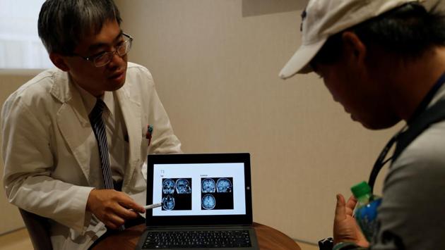 Dr Lin Ming-teng, head of the psychiatry department at Taipei Veterans General Hospital, shows X-ray images explaining the difference between a normal brain (L) and Chen Hong-zhi's brain during an appointment at the hospital, in Hsinchu. “After losing such a substantial portion of his brain, it is quite amazing for him to achieve what he is doing now,” Lin said, adding that Chen could only remember things he had done in the last five to 10 minutes. (Tyrone Siu / REUTERS)