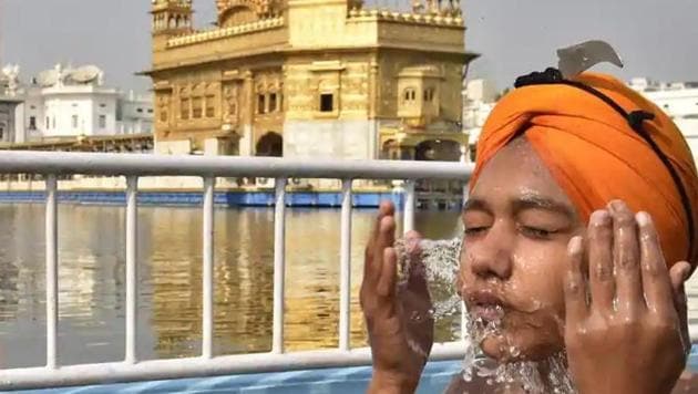 A devotee takes a dip in the holy sarovar (pond) at the Golden Temple, Amritsar.(Gurpreet Singh/HT Photo)