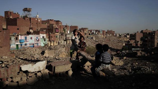 Children play on a make shift see-saw made out of a tree trunk in slum area Ezbet Khairallah, Cairo. Often, what lies behind the billboards are Cairo’s most overcrowded neighbourhoods, with shoddily built homes and dirt roads frequently inundated with sewage water. (Nariman El-Mofty / AP) Children play on a make shift see-saw made out of a tree trunk in slum area Ezbet Khairallah, Cairo. Often, what lies behind the billboards are Cairo’s most overcrowded neighbourhoods, with shoddily built homes and dirt roads frequently inundated with sewage water. (Nariman El-Mofty / AP)