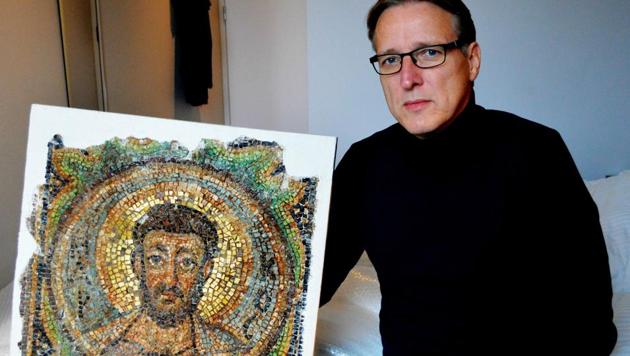 Dutch art detective Arthur Brand poses with the missing mosaic of St Mark, a rare piece of stolen Byzantine art from Cyprus, in a hotel room in The Hague.(AFP)