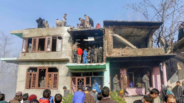 People inspect a damaged house where four Hizbul Mujahideen militants and a soldier were killed during an encounter, at Shopian district of South Kashmir on November 20.(PTI Photo)