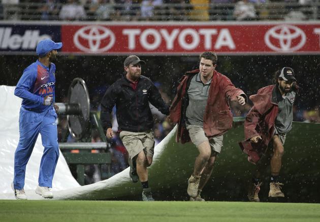 Players leave the field as ground staff cover the pitch after rain stopped play during the first T20 International cricket match between Australia and India in Brisbane. (AP)