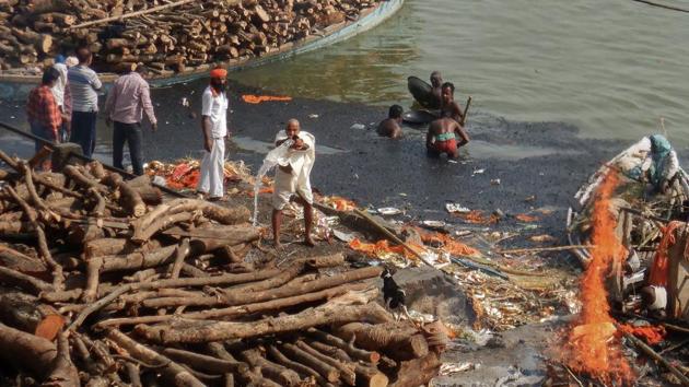 Men search for valuable metals such as gold and silver from dead bodies at Manikarnika Ghat. As the bodies wrapped in white shrouds and marigold flowers turn to ash, the remains are collected and sprinkled in the river. At the ghats, the Doms pass flaming torches to the families of the deceased, who ignite the wooden pyres dotting the riverside. (Dominique Faget / AFP)