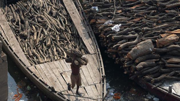 A worker unloads wood from a boat to be used at the traditional crematorium grounds at Manikarnika Ghat. Boats like this one arrive almost constantly at the ghats. (Dominique Faget / AFP)
