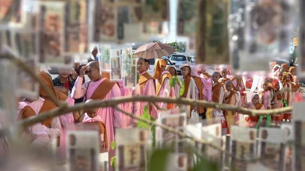 Novice monks walking during alms procession are seen through a hanging donations of Myanmar currency notes during Buddhist religious festivities in Yangon. (Ye Aung Thu / AFP) Novice monks walking during alms procession are seen through a hanging donations of Myanmar currency notes during Buddhist religious festivities in Yangon. (Ye Aung Thu / AFP)