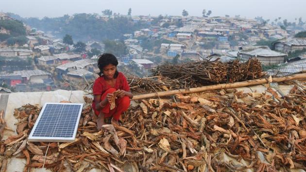 A young Rohingya refugee spreads out fire wood for drying on the roof of a shack, next to a solar panel, at the Hakimpara refugee camp in Bangladesh’s Cox’s Bazar district. (Dibyangshu Sarkar / AFP) A young Rohingya refugee spreads out fire wood for drying on the roof of a shack, next to a solar panel, at the Hakimpara refugee camp in Bangladesh’s Cox’s Bazar district. (Dibyangshu Sarkar / AFP)