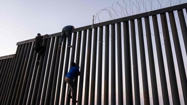 Men from Mexico climb the US-Mexico border wall in Playas de Tijuana, northwestern Mexico. (Guillermo Arias / AFP) Men from Mexico climb the US-Mexico border wall in Playas de Tijuana, northwestern Mexico. (Guillermo Arias / AFP)