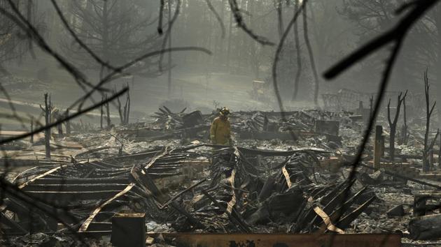 A firefighter searches for human remains in a trailer park destroyed in the Camp Fire, in Paradise, California. The massive wildfire that killed dozens of people and destroyed thousands of homes has been fully contained after burning for more than two weeks.(AP) A firefighter searches for human remains in a trailer park destroyed in the Camp Fire, in Paradise, California. The massive wildfire that killed dozens of people and destroyed thousands of homes has been fully contained after burning for more than two weeks.(AP)