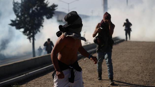 A migrant with his face covered runs from tear gas released by U.S border patrol near the fence between Mexico and the United States in Tijuana, Mexico. (REUTERS) A migrant with his face covered runs from tear gas released by U.S border patrol near the fence between Mexico and the United States in Tijuana, Mexico. (REUTERS)