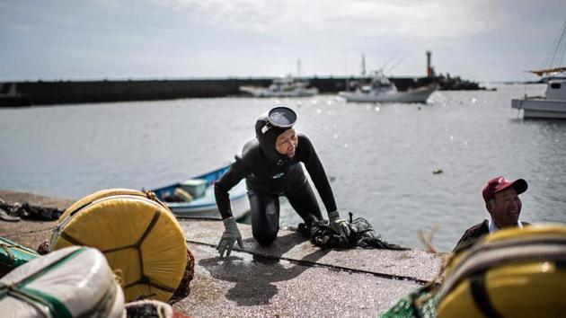 A freediving fisherwoman, known as an ‘ama’, climbs ashore after a dive in Toba. A group of Japanese grannies follows from a boat returning to shore. Clad in black wetsuits and bubbling with energy, they are part of a dwindling community of ama -- freediving fisherwomen. (Martin Bureau / AFP)
