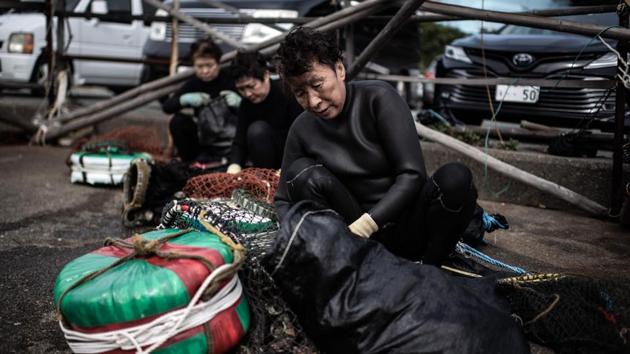 “I really feel like I am a mermaid among the fish, it’s a fantastic sensation,” says a beaming Hideko Koguchi. Back on shore, she kneels and counts the turban shells gathered by the group. Kitted out -- a mask covering her eyes and nose, flippers and a black wetsuit that replaced the white worn until the 1960s -- Koguchi sheds the weight of her years. (Martin Bureau / AFP)