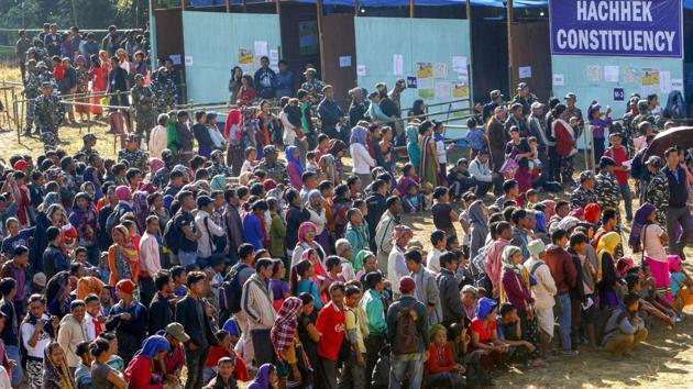 Security personnel stand guard as voters stand in a queue at a polling station during the state Assembly elections, at Kanhmun, Mizoram on Novermber 28.(PTI Photo)