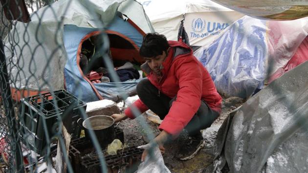A migrants prepares food. “It’s very difficult to survive here,” said Feroz Han Amanazay from Afghanistan, noting that the water is cold, there is no heating and the tents are too big to warm up. (Amel Emric / AP) A migrants prepares food. “It’s very difficult to survive here,” said Feroz Han Amanazay from Afghanistan, noting that the water is cold, there is no heating and the tents are too big to warm up. (Amel Emric / AP)