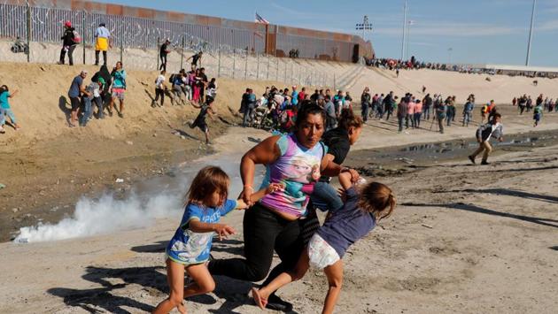 A migrant family, part of a caravan of thousands travelling from Central America en route to the United States, runs away from tear gas in front of the border wall between the US and Mexico in Tijuana, Mexico. (Kim Kyung-Hoon / REUTERS) A migrant family, part of a caravan of thousands travelling from Central America en route to the United States, runs away from tear gas in front of the border wall between the US and Mexico in Tijuana, Mexico. (Kim Kyung-Hoon / REUTERS)