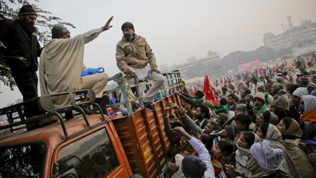 A volunteer tries to pacify farmers waiting for breakfast after they camped overnight. Five Gurdwaras in the Delhi region had extended their help to the farmers. Students from various universities also had turned out in large numbers to lend their support. (Altaf Qadri / AP)