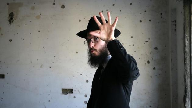 Rabbi Israel Kozlovsky gestures next to a wall riddled with bullet holes after the renaming of Nariman House as Nariman Light House, which was one of the targets of the November 26, 2008 attacks in Mumbai, Maharashtra on November 25, 2018. (Francis Mascarenhas / REUTERS)
