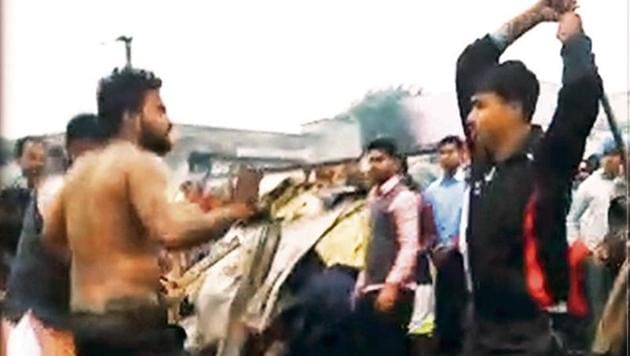 A screenshot of the video n shows a mob beating up a man with sticks in outer Delhi’s Kirari. Another screenshot (left) shows a policeman, standing as a mute spectator, in the background. (HT Photo) A screenshot of the video n shows a mob beating up a man with sticks in outer Delhi’s Kirari. Another screenshot (left) shows a policeman, standing as a mute spectator, in the background. (HT Photo)