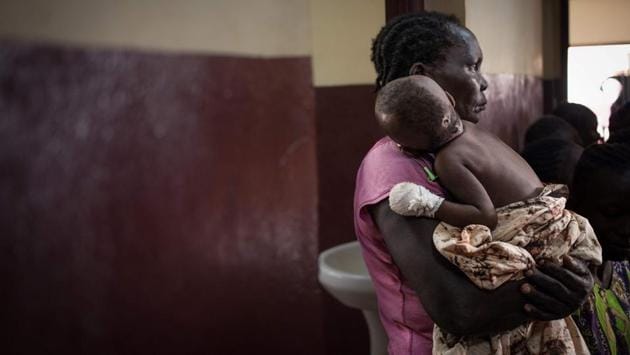 A mother stands among other parents waiting to see doctors, carrying weak, starving children, many hanging limply in their arms like half empty sacks of rice in a line snaking out the hospital into the dusty courtyard. (Florent Vergnes / AFP) A mother stands among other parents waiting to see doctors, carrying weak, starving children, many hanging limply in their arms like half empty sacks of rice in a line snaking out the hospital into the dusty courtyard. (Florent Vergnes / AFP)