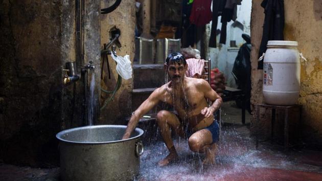 An Indian man bathes inside a workshop in the old quarters of Delhi. (Xavier Galiana / AFP) An Indian man bathes inside a workshop in the old quarters of Delhi. (Xavier Galiana / AFP)