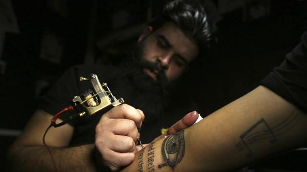A man gets a tattoo on his arm in a tattoo studio in Baghdad, Iraq. Years of war and unrest have inflicted physical and emotional scars on countless Iraqis. Aboud Abbas, who owns a tattoo studio in Baghdad, said around 20 people have come in this year asking for tattoos to conceal their scars, a 30 percent increase from last year. (Hadi Mizban / AP) A man gets a tattoo on his arm in a tattoo studio in Baghdad, Iraq. Years of war and unrest have inflicted physical and emotional scars on countless Iraqis. Aboud Abbas, who owns a tattoo studio in Baghdad, said around 20 people have come in this year asking for tattoos to conceal their scars, a 30 percent increase from last year. (Hadi Mizban / AP)