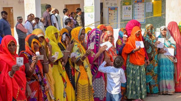 Voters show their identity cards as they wait in queues at a polling station to cast their votes for state Assembly elections in Jaipur on Friday.(PTI)