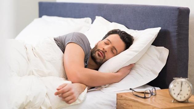 Man sleeping with alarm clock in foreground.(Getty Images/iStockphoto)
