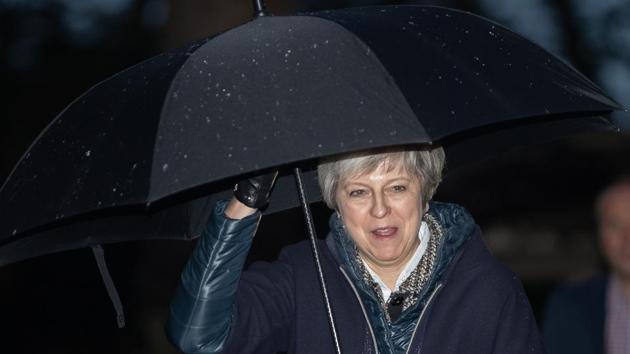 Britain's Prime Minister Theresa May shelters from the rain under an umbrella as she arrives for a church service near to her Maidenhead constituency, west of London on December 9, 2018.(AFP Photo)