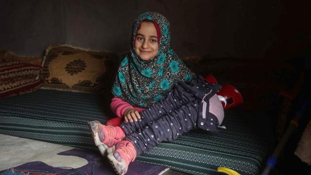 Merhi holds her prosthetic legs inside a tent at the IDP camp. Dressed in a pink sweater and matching shoes, Maya on Saturday was able for the first time to walk along the rutted roads of the Serjilla camp after arriving back. (Aaref Watad / AFP) Merhi holds her prosthetic legs inside a tent at the IDP camp. Dressed in a pink sweater and matching shoes, Maya on Saturday was able for the first time to walk along the rutted roads of the Serjilla camp after arriving back. (Aaref Watad / AFP)